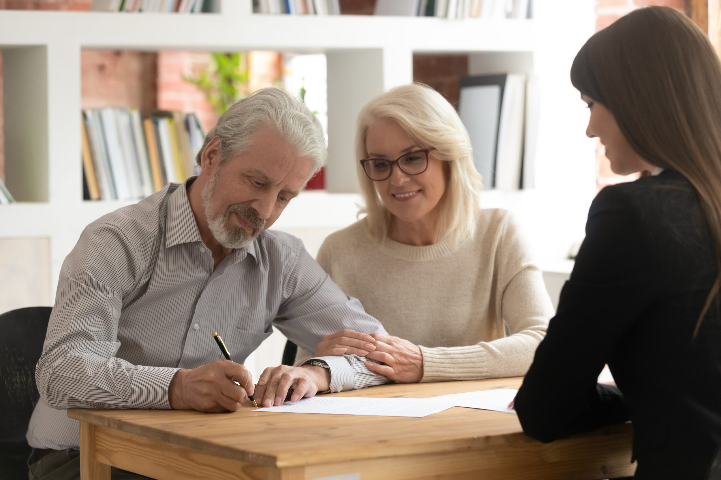 Happy mature husband and wife sign contract